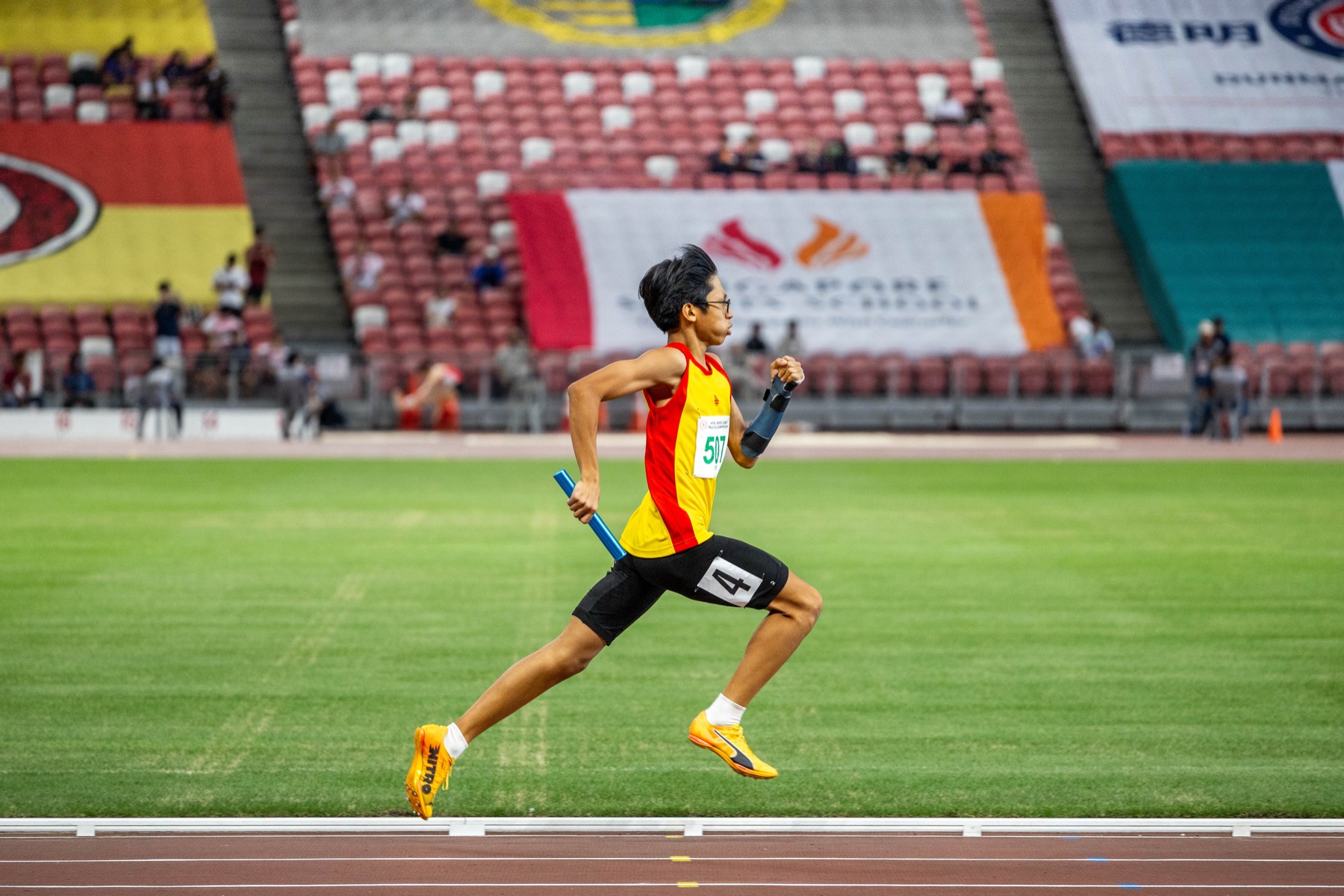 A relay runner mid-stride on an athletics track.